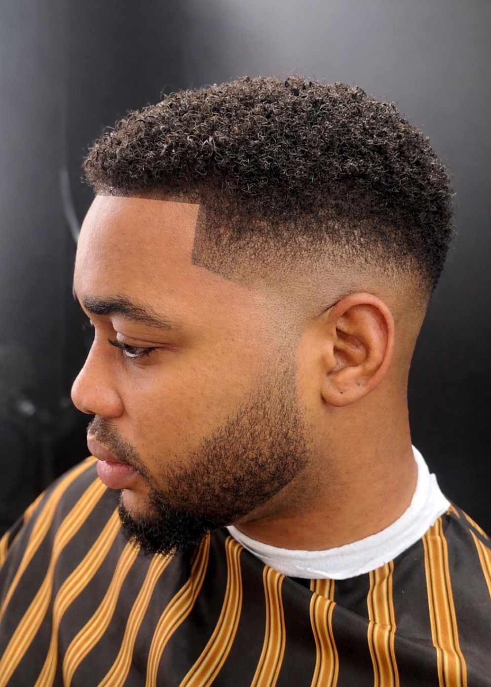 Coupe bouclée avec dégradé et barbe taillée